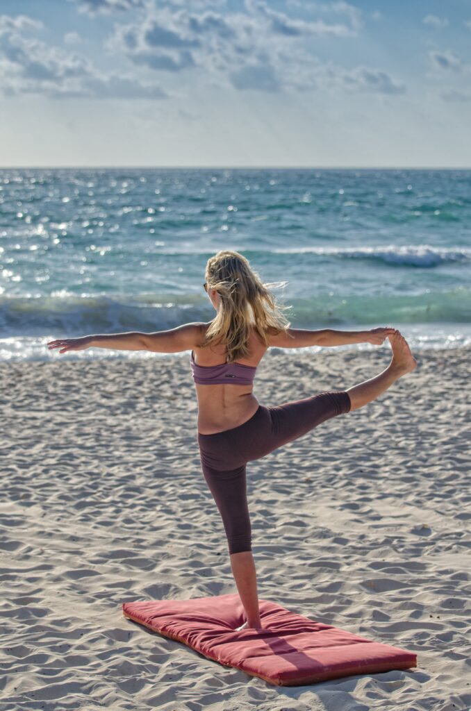 Mujer haciendo yoga en la playa relajante